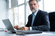 © opolja - Senior businessman working on laptop computer in the office.