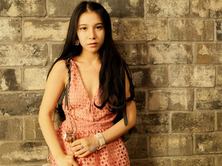 Beautiful young girl with long black hair posing with gray brick wall background. Vintage mode. Portrait of glamour Chinese stylish lady. Emotions, people, beauty and lifestyle concept.