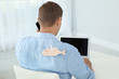 © New Africa - Man with paper fish on his back working with laptop at table indoors. April fool's day prank