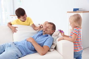 Sticker - Little children painting their father's face while he sleeping on couch at home. April fool's day prank