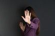 Woman showing stop gesture on dark background. Problem of sexual harassment at work