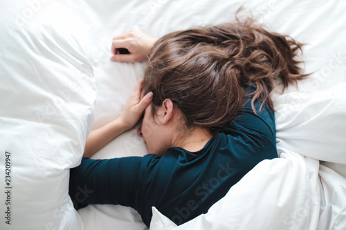 Fotografía young woman in bed holding her head
