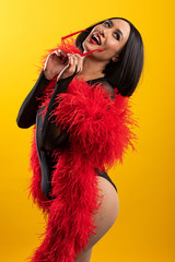 Fun, colorful portrait of pretty Asian woman wearing red feather boa and heart shaped glasses