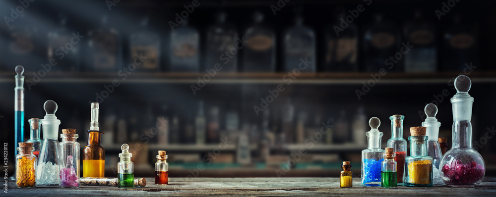 Vintage medications in small bottles on wood desk. Old medical, chemistry and pharmacy history concept background. Retro style. - obrazy, fototapety, plakaty 