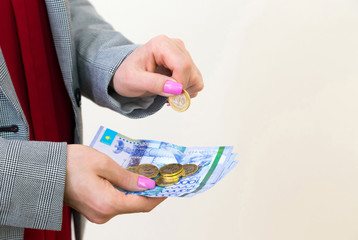 Closeup of woman's hands holding kazakhstani tenge banknotes and coins. Saving and spending concept