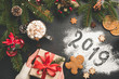 © Vladislav Noseek - 2019 Christmas or New Year background with gift box, fir tree, hot chocolate. 2019 written on flour on black concrete background. Festive Winter Holidays concept