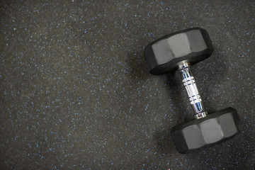 Dumbbell on black rubber floor in gym for exercise.