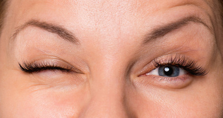 close up front portrait of beautiful happy woman face with gray eyes, wink