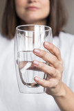 Fototapeta Łazienka - Beautiful charming woman drinking a big glass of water and wearing white clothes