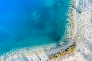 Abstract aerial image of a deep blue gravel lake in which sand is mined for the construction industry.