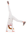Active little girl in grey sport clothes doing a handstand on white background