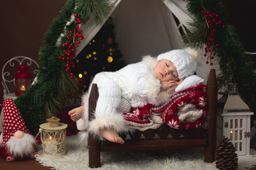 Canvas Print - Adorable little toddler baby boy dressed in canta claus costume, sleeping in baby bed in front of Christmas teepee