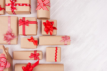 New Year celebration background - homemade craft paper gifts with red ribbons and bows on white wood plank, top view, border.