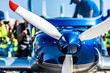Closeup view of white propeller with red endings of the shiny blue sport plane nose
