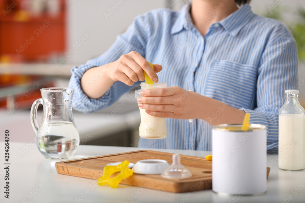 Woman preparing baby formula at table