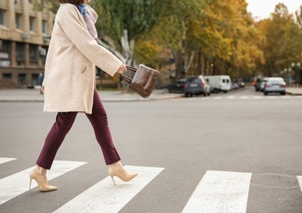 Beautiful fashionable woman crossing road