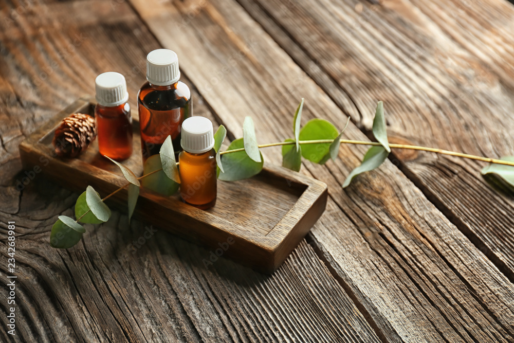 Bottles of eucalyptus essential oil on wooden background