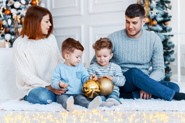 Wall Mural - A family of four hugging in front of the christmas tree. New year's eve. Cozy holiday at the fir-tree. love, happiness and big family concept