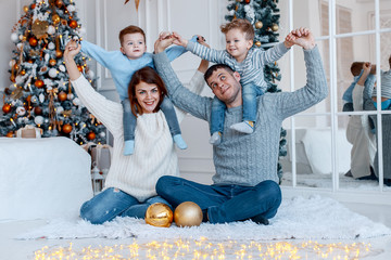 Wall Mural - A family of four hugging in front of the christmas tree. New year's eve. Cozy holiday at the fir-tree. love, happiness and big family concept