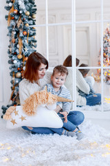 Wall Mural - Mother and son in front of the christmas tree with candles and gifts having fun. New year's eve. Cozy holiday at the fir-tree. love, happiness and big family concept