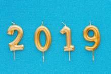 Happy New Year 2019. Gold Shiny Number, Candles On Colored Background. Christmas , Festive Background.