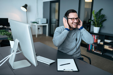 Wall Mural - Casual businessman with headset talking and laughing in modern office.