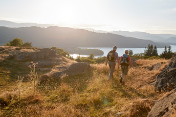 Rear View Of Senior Couple Walking On Top Of Hill On Hike Through Countryside In Lake District UK