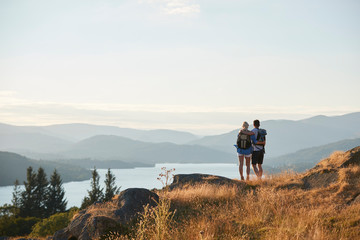 rear view of couple hugging on top of hill on hike through countryside in lake district uk