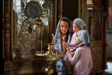 Young Mother And Her Little Blond Caucasian Daughter With Candles In Orthodox Russian Church