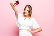 © master1305 - Portrait of a young attractive woman making selfie photo with smartphone on a pink studio background