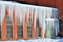 Long, Big And Dangerous Icicles On A Brick House Roof