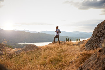 a young mixed race man standing alone on a rock admiring the lake view, side view