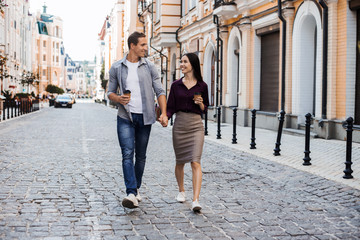 Multiracial couple walking in their eurotrip. Caucasian and asian ethnic, both are smiling and looking each other. They could be friends or in a relationship. Lifestyle and love concepts. Eurotour