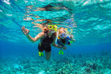 Fototapeta Do akwarium - Happy family - mother, kid in snorkeling mask dive underwater with tropical fishes in coral reef sea pool. Show by hands divers sign OK. Travel lifestyle, beach adventure on summer holiday with child.