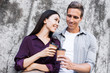 © Marharyta Hanhalo - Hurry for meeting. Two young business people walking outside on the city street drinking hot coffee talking smiling joyful close-up. Romantice relationship, love affair at work