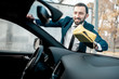 © rh2010 - Smiling businessman dressed in a suit wiping windshield of his car with yellow microfiber on a self service car wash
