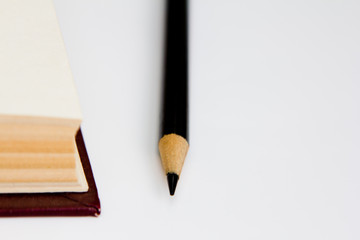 black pencil and red book top view isolated on white background. information resources.