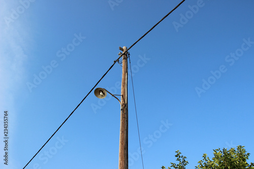 Fotografie, Obraz Old street lamp post electricity pole wires wooden blue sky