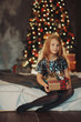 Merry Christmas!happy kid girl with magic gift at home near Christmas tree and fireplace