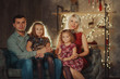 Christmas and  Holidays family! Cheerful parents and and two little children sitting together on soft sofa near Christmas tree  in living room