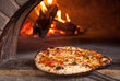 © Lori Eanes - Pizza pie being taken out of a wood burning oven