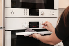 Woman Adjusting Electric Oven In Kitchen, Closeup