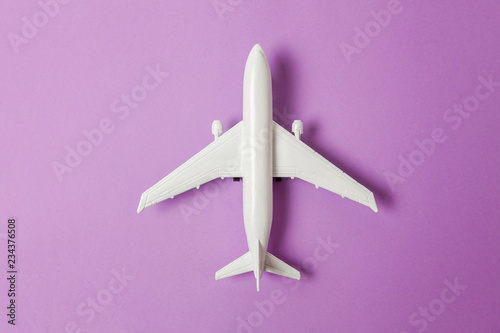 Fényképezés Simply flat lay design miniature toy model plane on violet purple pastel colorful paper trendy background