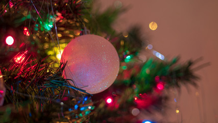 Brightly colored, cheery Christmas tree ornaments hung up with lights and tinsel