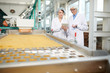 © Seventyfour - Portrait  of  two  women doing  production quality inspection in food factory standing by conveyor belt and using digital tablet, copy space