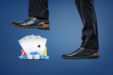 Poster - businessman's shoes stepping on pack of cards, dice and stacks of chips on blue background.