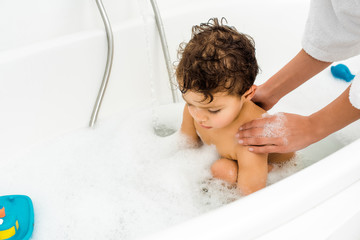  Female hands washing toddler boy in white bathroom