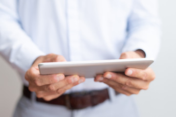 Closeup of business man using tablet computer. Man browsing on digital device. Technology and communication concept. Cropped front view.