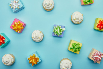 Wall Mural - Top view of delicious cupcakes and gifts on blue background