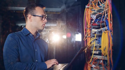 Male programmer checking server equipment in a room, close up.